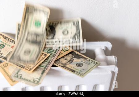 Ein Heizungs- und Energiekostenkonzept mit einem Haufen US-Dollar, der von einem Zentralheizungskörper steigt. Stockfoto