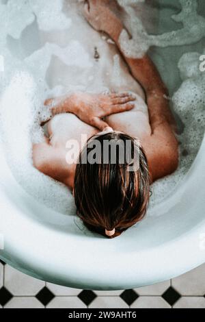 Frau, die sich in einem Rolltop-Bad mit Blasen entspannt Stockfoto