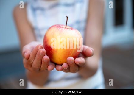 Die Hand eines Kindes, das einen saftigen Apfel in Nahaufnahme hält, um das Wohlbefinden der Ernährung zu gewährleisten. Stockfoto