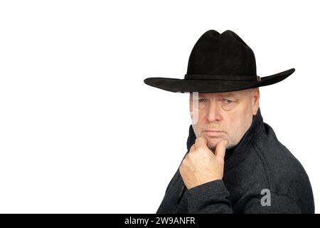 Kaukasischer Mann mittleren Alters in Cowboy Hut Deep in Thought on White Background - reflektierendes, introspektives und Farmer kontemplatives Konzept. Stockfoto