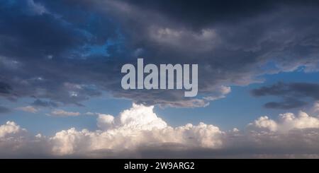 Dramatischer Himmel mit dunklen stürmischen Wolken und weißen Cumuluswolken am Horizont Stockfoto