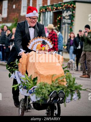 East Hoathly, Großbritannien. Dezember 2023. Kinderwagenrennen am Boxing Day: Teams in schicken Kleidern laufen durch das Dorf East Hoathly in East Sussex und sammeln Spenden für lokale Wohltätigkeitsorganisationen. Die jährliche Veranstaltung beginnt und endet im Kings Head Pub im Zentrum des Dorfes. Quelle: Jim Holden/Alamy Live News Stockfoto