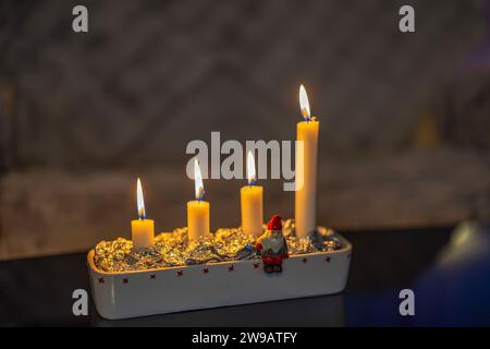 Nahaufnahme von vier brennenden Kerzen in einem traditionellen Adventskerzenhalter während der Weihnachtsfeier. Stockfoto