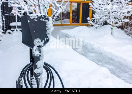 Nahaufnahme einer Ladestation für Elektrofahrzeuge auf einem privaten Parkplatz an einem Wintertag. Stockfoto