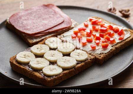 Verschiedene Sandwiches mit Salami, Schokolade und Banane, Frischkäse und rotem Pfeffer zum Frühstück oder Brunch Stockfoto