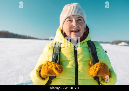 Ältere Frau aus den 60er Jahren, die auf dem Hügel relaxt. Frau trinkt heißen Tee aus der Thermotasse und genießt den Panoramablick auf den Stadtpark. Stockfoto