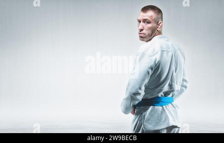 Ein starker Mann im Kimono schaut ihm über die Schulter. Konzept von Karate, Sambo, Jujitsu. Gemischte Medien Stockfoto