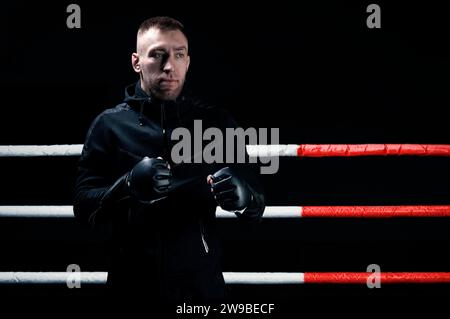 Ein gemischter Kampfkünstler steht mit erhobenen Händen. Konzept von mma, ufc, thai-Boxen, klassischem Boxen. Gemischte Medien Stockfoto