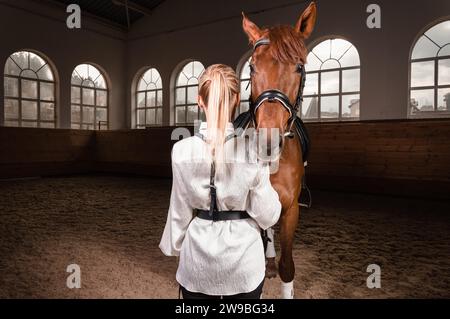 Bild einer blonden Frau in Form einer Reiterin von hinten. Pferderennen und Reitsport-Konzept. Gemischte Medien Stockfoto