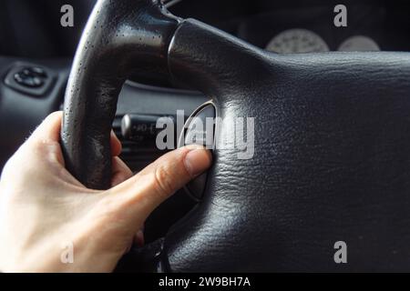 Ein Mann fährt ein Premium-Auto, seine Hand ist am Lenkrad, er drückt die Tempomattaste Stockfoto