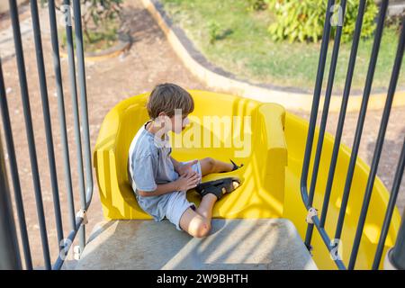 Abfahrtsski. Der Junge sitzt oben auf den Rutschen und rutscht nach unten. Stockfoto