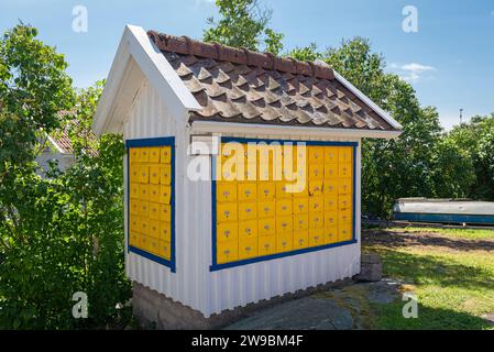 Weiße Holzhütte mit nummerierten gelben Briefkästen in der Hafenstadt Stocken auf der Insel Orust an der Westküste Schwedens Stockfoto