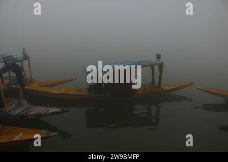 25. Dezember 2023, Srinagar Kashmir, Indien: Ein Mann rudert ein Boot auf dem Wasser des Dal Sees während eines nebeligen und kalten morgens in Srinagar. Das lokale Wetteramt hat prognostiziert, dass die vorherrschenden Wetterbedingungen bis zum 31. Dezember in der Himalaya-Region anhalten werden. Die Wetterabteilung warnt davor, dass es zu einem stärkeren Temperaturabfall kommen wird und das nebelige Wetter die Region weiterhin umhüllt. Kaschmir befindet sich derzeit zwischen einer 40-tägigen harten Winterperiode, dem kältesten Teil des Winters, der vom 21. Dezember bis zum 29. Januar jedes Jahres beginnt. Am 25. Dezember 2023 In Srinagar Kaschmir, Indien. (Phot Stockfoto