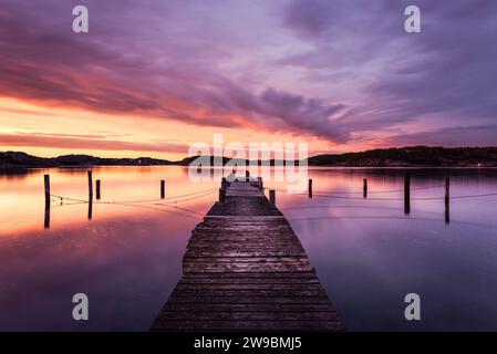 Leuchtende Wolken in der Abenddämmerung über einem Holzsteg auf der Insel Malö im Archipel der schwedischen Westküste Stockfoto