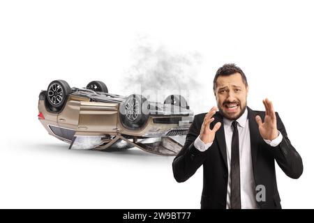 Verängstigter Mann, der vor einem abgestürzten SUV auf weißem Hintergrund steht Stockfoto