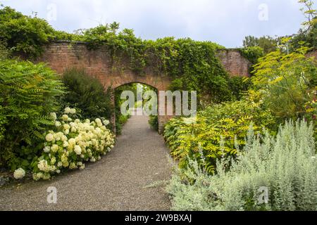 Backsteinbogen auf einem wunderschönen englischen Gartenpfad Stockfoto