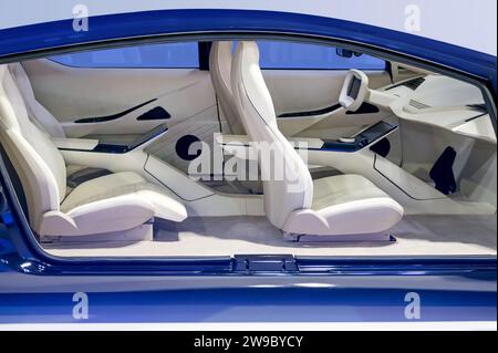 Seitenansicht des futuristischen Fahrzeuginnenraums mit gemütlichen Sitzen mit Kopfstützen in blauer Karosserie und Armaturenbrett, das das Lenkrad im Werk bei Licht ersetzt Stockfoto