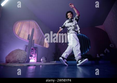 Junge männliche Hip-Hop-Tänzerin demonstriert Moves in zeitgenössischem Kunstraum mit schwachem Licht Stockfoto