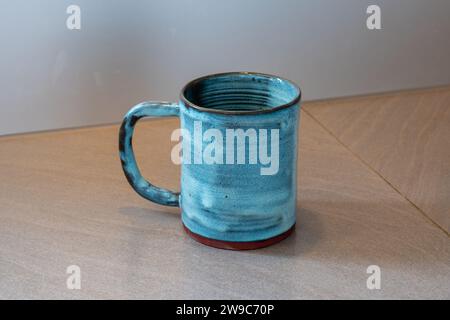 Blauer Becher auf hölzerner Küchenzeile. Hochwertige Fotos. Hobby- und Nebenbeschäftigung. Töpferwaren, Töpfe Stockfoto