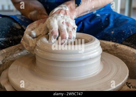 Potter wirft in einem Studio einen Topf aufs Steuer. Hochwertige Fotos. Hobby, Nebeneinander, Aktivität Stockfoto