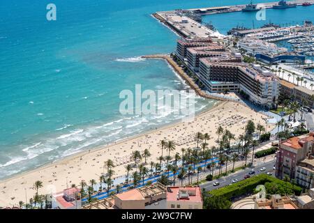 Strand mit Liegen und Schwimmen, auf dem Sand und im Meer, in der Nähe des Hafens von Alicante. Hochwertige Fotos Stockfoto