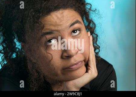 Eine afroamerikanische Frau, die den Kopf in der Hand hält, mit dem verwirrten und verwirrten Ausdruck Stockfoto