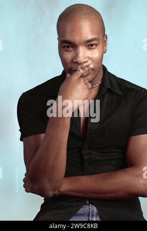Porträt eines afroamerikanischen Mannes mit einem rasierten Kopf, der ein schwarzes Hemd auf einem normalen Studio-Hintergrund trägt Stockfoto