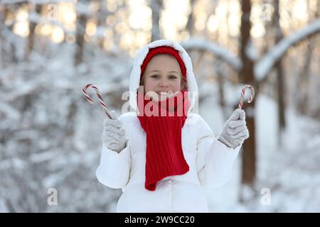 Süßes kleines Mädchen mit Zuckerstangen im Winterpark Stockfoto