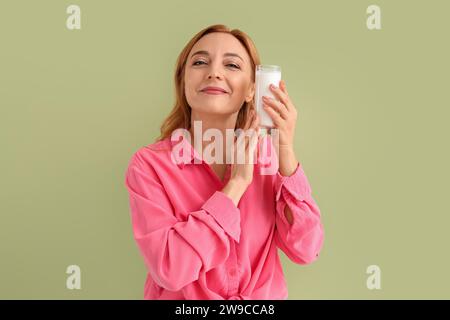 Reife Frau mit einem Glas Milch auf grünem Hintergrund Stockfoto