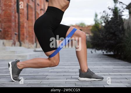 Frau, die Sport macht mit Fitness-Elastikband draußen, Nahaufnahme Stockfoto