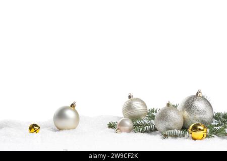 Wunderschöne Weihnachtskugeln, Tannenzweig und Schlittenglocken auf Schnee vor weißem Hintergrund Stockfoto