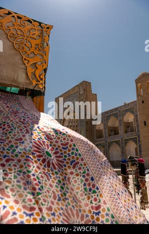 Schöne ethnische Stoffe, die mit dem Wind wehen, neben der alten Madrasah, Buchara, Usbekistan. Selektiver Fokus mit Kopierraum für Text Stockfoto