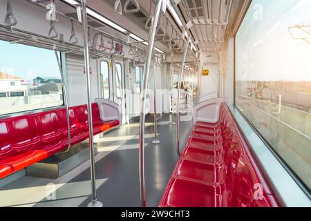 Rote Kunststoffsitze und Chrom-Handläufe in einem elektrischen Zugwagen. Stockfoto