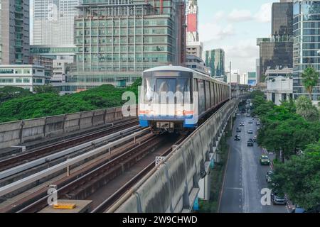 E-Bahnwagen fahren entlang der Strecke im Sky Railway Road Viadukt durch die moderne Stadt mit Gebäuden, Wolkenkratzern und Bäumen Stockfoto