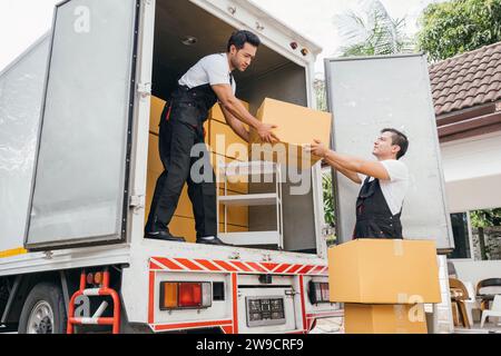 Arbeiter in Uniform stellen Teamarbeit aus, die Kartons aus dem fahrenden Lkw für den Kunden entladen Stockfoto