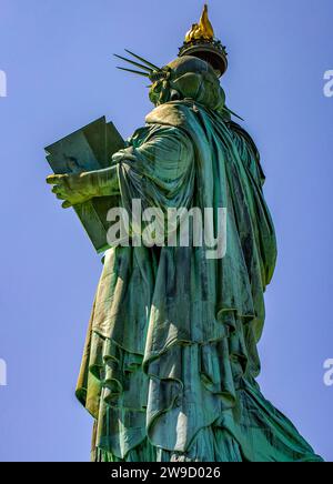 Großes vertikales Rückfoto der Freiheitsstatue mit ihrer Fackel an einem sonnigen Tag in Manhattan, bekannt als die Dame von New York City USA. Stockfoto