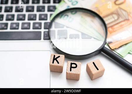 Lupe über Text-KPI auf Holzwürfelblöcken auf weißem Bürotisch. Leistungsindikator Stockfoto