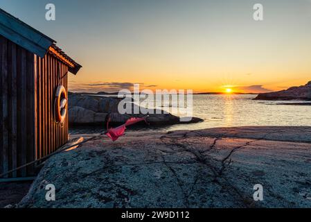 Holzhütte im glühenden Sonnenuntergang auf den Felsen im Naturschutzgebiet Tjurpannan im Archipel der schwedischen Westküste Stockfoto