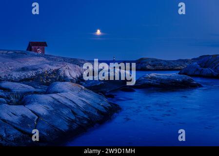 Der Mond über einer Holzhütte auf Felsen am Ufer des Skagerrak im Naturschutzgebiet Tjurpannan im Archipel der schwedischen Westküste Stockfoto