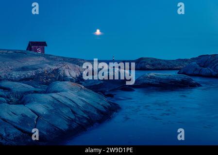 Der Mond über einer Holzhütte auf Felsen am Ufer des Skagerrak im Naturschutzgebiet Tjurpannan im Archipel der schwedischen Westküste Stockfoto