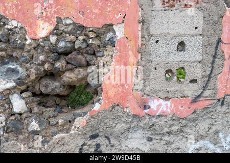 Detail einer zerstörten farbigen Hauswand mit Steinen und Löchern Stockfoto