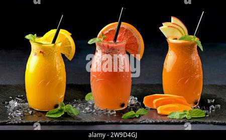 Gläser mit frisch gepresstem Saft. Apfel-, Karotten-, Orangen- und Grapefruitsaft auf schwarzem Hintergrund Stockfoto