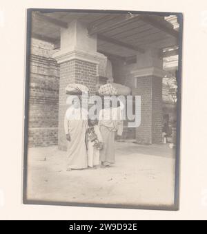 Ein Mann und eine Frau mit Dingen auf dem Kopf und ein Kind zwischen ihnen an einer Buddha-Statue, Myanmar, 1907 fotografieren Myanmar fotografische Unterstützung Gelatine Silberdruck Stockfoto