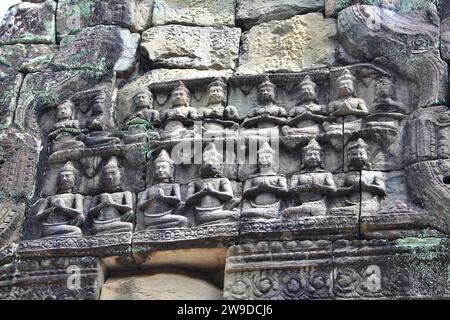 Detail von zwei Reihen identischer Sitzfiguren, die in Hochrelief über einem Eingang zwischen den Ruinen des archäologischen Parks Angkor in Kambodscha gemeißelt wurden Stockfoto