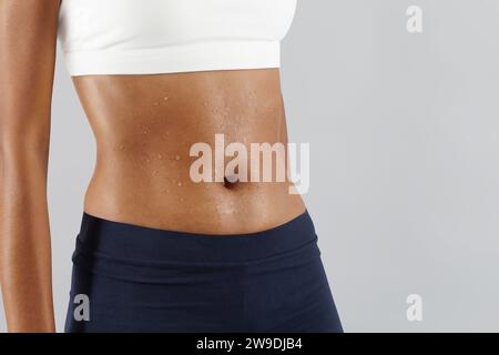 Fitnesstraining, Frau schwitzt Bauch, Schweißtropfen auf der Haut Bauch Nahaufnahme, afrikanische lateinamerikanische Athletin in Sportbekleidung, Sportswoman do exer Stockfoto