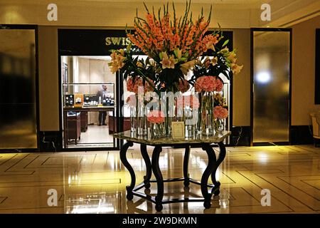 Eine schicke Hotellobby mit üppigen Blumenarrangements mit Hortensien, Lilien und Gladiolen in verschiedenen Rosa-Tönen mit sanfter, atmosphärischer Beleuchtung Stockfoto