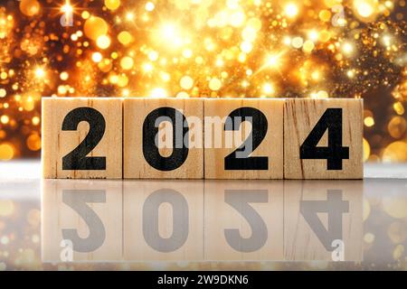 27. Dezember 2023: Neujahr und Silvester Konzept, das Jahr 2024 auf Holzwürfeln vor funkelndem Hintergrund FOTOMONTAGE *** Neujahr und Silvester Konzept, die Jahreszahl 2024 auf Holzwürfeln vor funkelndem Hintergrund FOTOMONTAGE Stockfoto