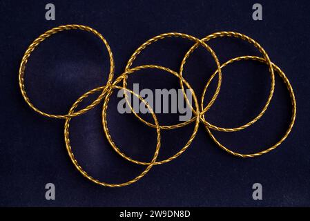 24k (24 Karat) Türkisch Gold Twist Armband steht in einem Haufen auf einem dunkelblauen Hintergrund im Goldladen Stockfoto