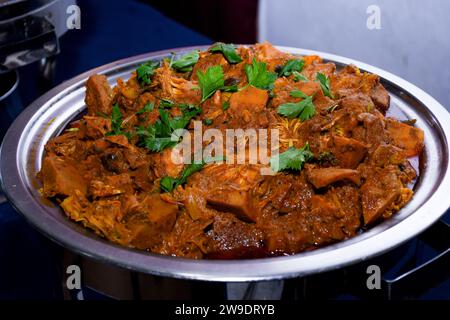Leckeres Butter-Hühnchen-Curry-Gericht aus indischer Küche in Buffet, Orangenscheiben-Dekorationen. Stockfoto