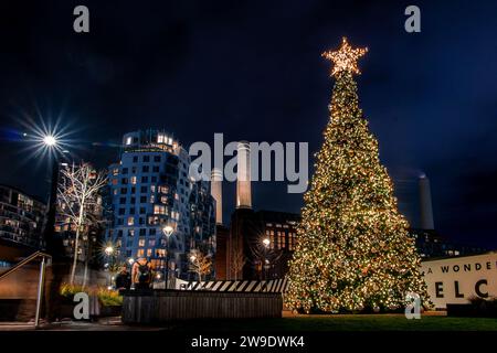 Weihnachtslichter und ein Weihnachtsbaum vor dem berühmten Kamin der Battersea Power Station bei Nacht Stockfoto